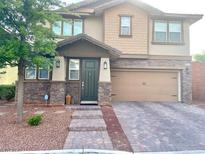 Charming two-story home with tan siding, stone accents, and a paved driveway at 5627 Spanish Valor Rd, Las Vegas, NV 89135