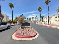Inviting community entrance with lush landscaping, mature palm trees, and clear blue skies at 698 S Racetrack Rd # 322, Henderson, NV 89015