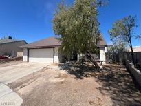 Modest single story home with an attached two car garage and mature trees at 7300 Mountain Moss Dr, Las Vegas, NV 89147