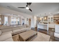 Spacious living room with modern fan, wood floors, neutral tones, and access to the dining and kitchen area at 167 Thunder Plains Way, Henderson, NV 89012