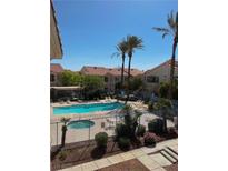 Community pool and hot tub surrounded by lush landscaping and palm trees at 1881 W Alexander Rd # 1128, North Las Vegas, NV 89032