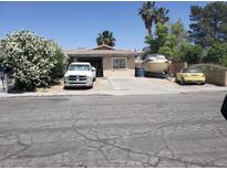 Modest home with mature flowering bush, large truck, boat, and small car on driveway at 47 Locustwood St, Las Vegas, NV 89110