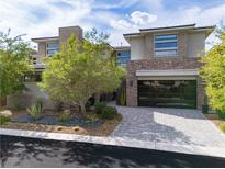 Stunning two-story home featuring a modern design, stone accents, glass garage door and beautifully landscaped front yard at 5 Moonfire Dr, Las Vegas, NV 89135