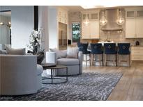 Open-concept living room with modern furnishings flowing into a bright kitchen featuring barstool seating at 5 Moonfire Dr, Las Vegas, NV 89135