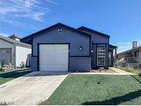 Charming single-story home with an attached garage, front lawn, and a concrete driveway against a bright blue sky at 6215 Don Zarembo Ave, Las Vegas, NV 89108