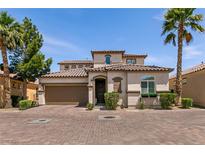 Charming two-story home with a tile roof, palm trees, and a brick driveway on a sunny day at 63 Via Di Mello, Henderson, NV 89011