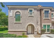 Two-story townhome featuring stucco exterior, arched entryway, and well-maintained landscaping at 10001 Peace Way # 2335, Las Vegas, NV 89147