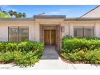 Inviting home entrance featuring a secure gated doorway and lush, mature landscaping at 2480 Domingo St, Las Vegas, NV 89121