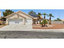 Charming single-story home featuring a two-car garage, solar panels, and desert landscaping with palm trees at 6328 Yankee Meadow Cir, Las Vegas, NV 89130