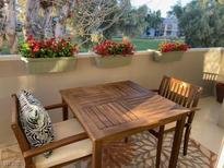Relaxing balcony with a wooden table, chairs, and vibrant red flowers in hanging planters at 778 Oakmont Ave # 312, Las Vegas, NV 89109