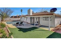 This backyard features a sparkling pool, artificial turf, and a covered patio, perfect for outdoor relaxation and entertaining at 976 El Camino Way, Boulder City, NV 89005