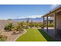 Beautiful backyard featuring a covered patio, artificial turf, and desert landscaping with mountain views at 1047 Atkins Ln, Mesquite, NV 89027
