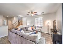 Bright living room with a plush gray sectional sofa, ceiling fan, and wood-look flooring at 10636 Colter Bay Ct, Las Vegas, NV 89129
