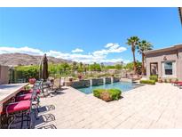 Stunning backyard pool featuring a bar with seating, palm trees, and beautiful desert views at 2539 Turtle Head Peak Dr, Las Vegas, NV 89135