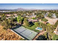 Expansive aerial view of a private estate featuring a tennis court, pool, and mature landscaping at 3455 Five Pennies Ln, Las Vegas, NV 89120
