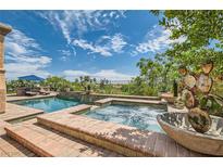 Relaxing backyard pool and spa with lounge chairs, blue umbrella, and desert landscaping under a bright sky at 4980 Pensier St, Las Vegas, NV 89135