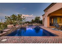 Backyard pool area features a brick-laid patio, a cascading waterfall and access to the home's covered patio and outdoor living space at 4980 Pensier St, Las Vegas, NV 89135