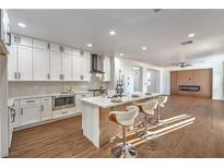 Modern kitchen features white cabinets, stainless steel appliances, an island with bar seating, and wood-look flooring at 1136 Casady Hollow Ave, Henderson, NV 89012