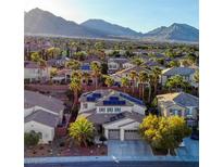 Aerial view of a neighborhood showcasing a home with solar panels surrounded by lush landscaping and mountain views at 11550 Velicata Ct, Las Vegas, NV 89138
