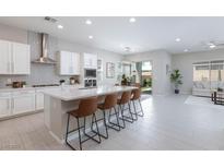 Bright, open kitchen featuring a large island with seating, modern appliances, and seamless flow to the living area at 10251 Tiger Milkweed St, Las Vegas, NV 89141