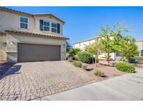 Two-story home featuring a two-car garage, landscaped front yard, and a brick-paved driveway at 104 Pollentia Ave, North Las Vegas, NV 89084