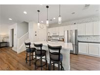 Bright, modern kitchen features white cabinets, stainless steel appliances, and island with bar seating at 2606 Marvel Astoria St, Henderson, NV 89044