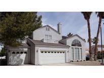 Two-story home featuring a three-car garage and classic architecture, complemented by mature trees at 2830 Queens Courtyard Dr, Las Vegas, NV 89109