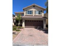 Two-story home featuring a tile roof and a brick paved driveway leading to a two car garage at 10974 Fintry Hills St, Las Vegas, NV 89141