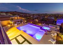 Inviting pool and spa with an outdoor kitchen, set against a picturesque mountain and city backdrop at twilight at 2153 King Crest Ct, Henderson, NV 89052