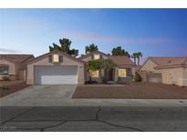 Charming single-story home with a two-car garage and desert landscaping at dusk at 5900 Red Umber Ave, Las Vegas, NV 89130