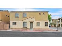 Two-story tan home with a desert landscape and a bench in front at 6928 Smiling Cloud Ave, Henderson, NV 89011