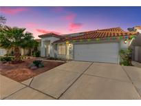 Charming single-story home featuring a red tile roof, two-car garage, and desert landscaping at sunset at 7874 Trail Boss Ct, Las Vegas, NV 89113