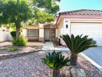 Charming single-story home features a well-manicured front yard, two palm trees and a two-car garage at 1812 Jack Rabbit Way, Las Vegas, NV 89128