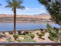 Scenic lake view featuring a palm tree, lush landscaping, and mountains in the background at 20 Via Mantova # 208, Henderson, NV 89011