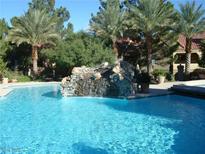 Stunning community pool featuring a rock waterfall and surrounded by lush landscaping and towering palm trees at 2200 S Fort Apache Rd # 2071, Las Vegas, NV 89117