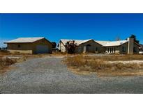 Desert property features a neutral-toned single-story home with a detached garage and gravel driveway at 3750 S Rainbow Ave, Pahrump, NV 89048