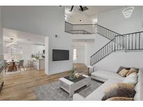 Bright, open-concept living room featuring a staircase and modern furnishings, flowing into the dining and kitchen area at 5466 Silverheart Ave, Las Vegas, NV 89142