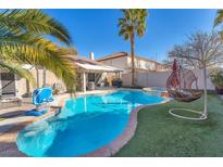 Inviting pool with a basketball hoop, lounge area, hot tub, and unique egg chair with palm trees under a bright blue sky at 10113 Walhalla Plateau Ct, Las Vegas, NV 89148