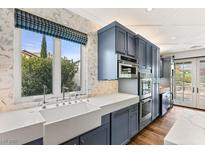 Bright kitchen with marble countertops, oversized window with a view, and custom blue cabinets at 11578 Suburban Rd, Las Vegas, NV 89135