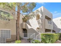 Two-story condo showcasing landscaped grounds, and stairs leading up to private balconies on a sunny day at 1900 Mountain Hills Ct # 203, Las Vegas, NV 89128