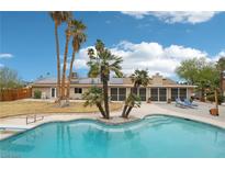 Backyard pool features a diving board and an inviting lounge area surrounded by swaying palm trees and blue skies at 3155 Duneville St, Las Vegas, NV 89146