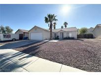 Single story home featuring desert landscaping, a two car garage, and a tall palm tree at 4651 Wild Oak Way, North Las Vegas, NV 89031