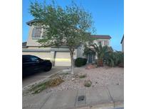 Charming two-story home boasts a landscaped front yard, mature tree, two-car garage, and inviting curb appeal at 82 Scorpios Island St, Henderson, NV 89012