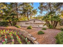 Beautifully landscaped entrance to the Sun City Summerlin, a Del Webb community, with colorful flowers and palm trees at 9409 January Dr, Las Vegas, NV 89134