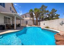 Sparkling pool with rock feature, covered patio, and lush landscaping create a backyard oasis at 9516 Belgate Ct, Las Vegas, NV 89129