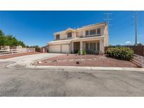 Two story home featuring a two-car garage, desert landscaping, and a charming white picket fence at 10290 Marion Morrison Ct, Las Vegas, NV 89183