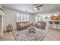 Inviting living room with neutral tones, area rug, ceiling fan, and comfortable seating at 10294 Running Falls St, Las Vegas, NV 89178