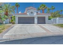 Two-car garage with a patterned concrete driveway and mature palm trees at 217 Windsong Dr, Henderson, NV 89074