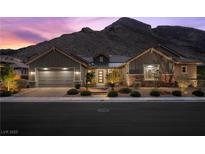 Stunning exterior of single Gathering home featuring a mountain backdrop, lush landscaping, and a two car garage at 3131 Reverence Heights Ln, Las Vegas, NV 89138