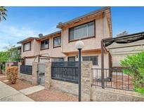 Two story townhome with a stone and iron fence and desert landscaping at 4339 Spencer St # 15, Las Vegas, NV 89119